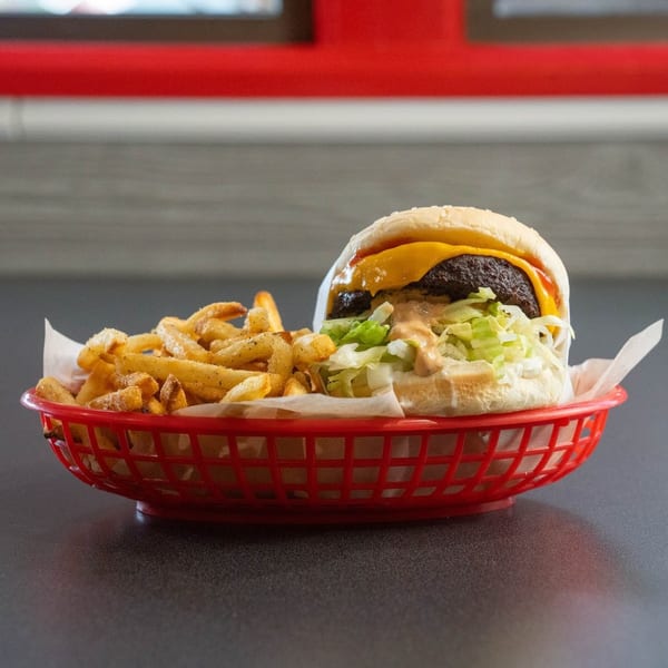 Cheeseburger with lettuce, special sauce, and a side of seasoned fries in a red basket.